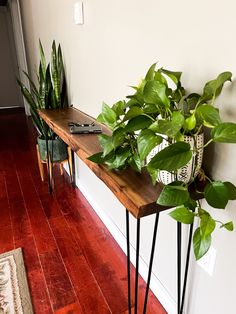 some plants are sitting on top of a wooden table in the corner of a room