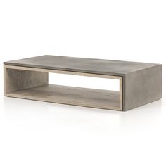 a concrete coffee table sitting on top of a white floor next to a wooden shelf