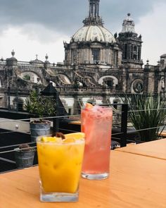 two drinks sitting on top of a table next to each other in front of a building