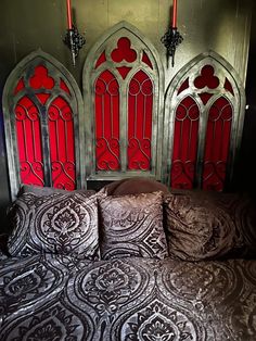 a bed with two red stained glass windows on the headboard and pillows in front of it