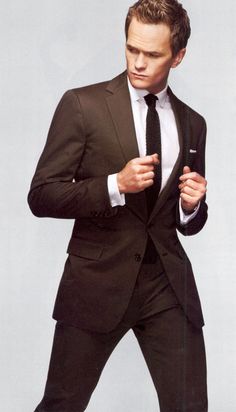 a man in a suit and tie is posing for the camera with his hands on his hips