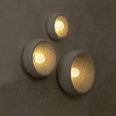 three lights that are on the side of a wall in a room with concrete walls