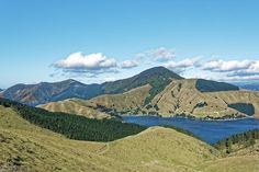 the mountains are covered in green grass and blue water