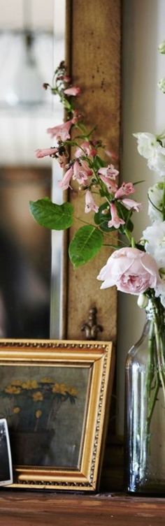 flowers are in vases on a shelf next to an old photo and framed photograph