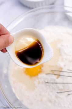 an egg being whisked with brown liquid in a glass bowl on top of a table