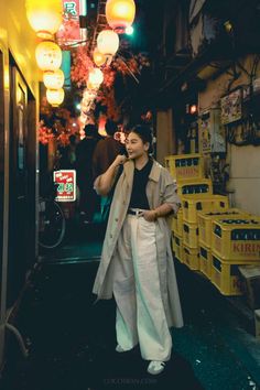 a woman is standing in the middle of an alleyway with lanterns hanging above her