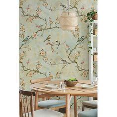 a dining room table with two chairs and a bird on the branch wallpaper behind it