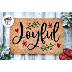 a door mat with the word joyful written on it next to red shoes and succulents