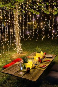 a picnic table with candles, plates and fruit on it in the middle of a grassy area