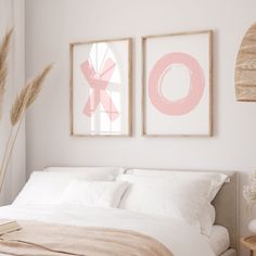 two paintings on the wall above a bed in a room with white sheets and pillows