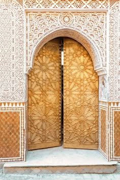 an intricately carved wooden door in the middle of a building with stone work on it