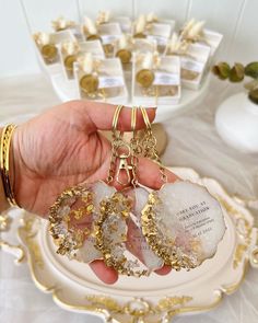 a person holding three pieces of glass in their hand on a plate with gold trimmings