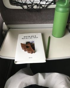 an open book sitting on top of a table next to a green cup and pen