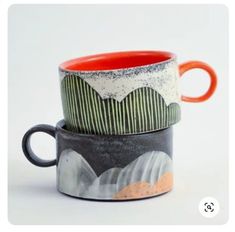 two coffee mugs sitting side by side on top of each other in different designs