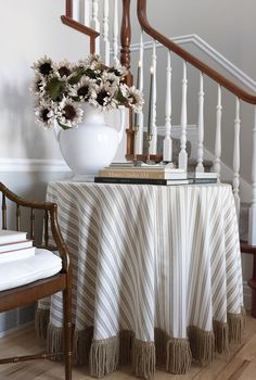 a white vase with flowers sitting on top of a table next to a stair case