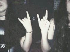 two young women making the peace sign with their hands while sitting down in a dark room