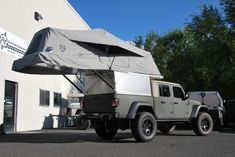 a truck with an awning attached to it parked in front of a white building