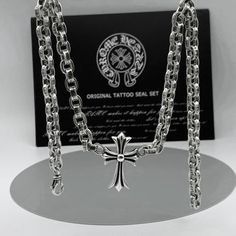 a silver chain with a cross on it and a business card in the back ground