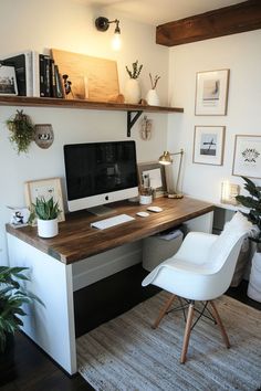 a desk with a computer, chair and potted plants on it in a home office