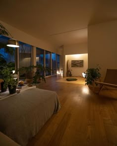 an empty bedroom with wooden floors and large windows at night, lit by lights on the wall