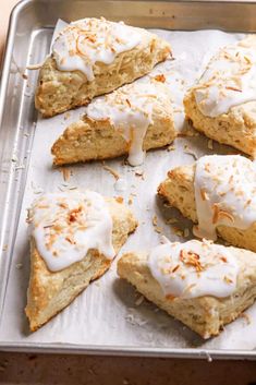 scones with white frosting and orange sprinkles on a baking sheet