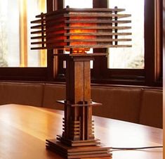 a wooden table with a lamp on it in front of a window and windowsill