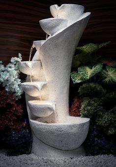 a water fountain is shown in front of some flowers