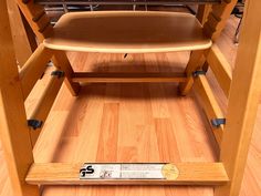 a wooden high chair sitting on top of a hard wood floor