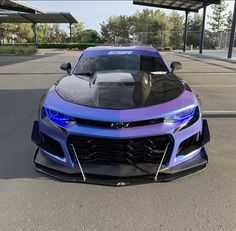 a blue and black sports car parked in a parking lot next to a gas station