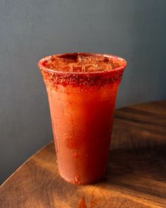 a red drink sitting on top of a wooden table