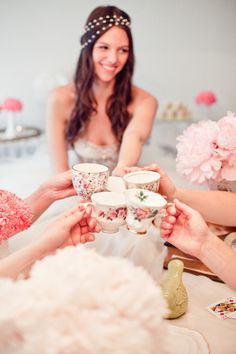 a group of women sitting around a table with cups and saucers in their hands