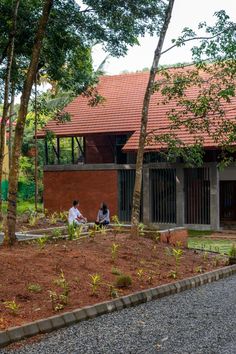 two people sitting on a bench in front of a building with red tile roofing