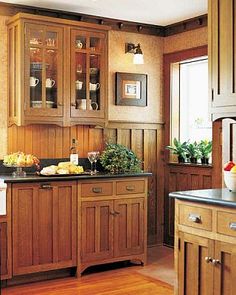 a kitchen with wooden cabinets and black counter tops, along with wood flooring that matches the walls