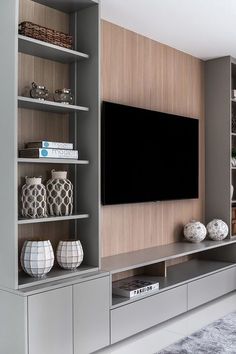 an entertainment center with bookshelves, shelves and a flat screen tv mounted on the wall