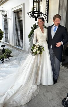 the bride and groom are standing outside in front of their wedding venue, dressed in white