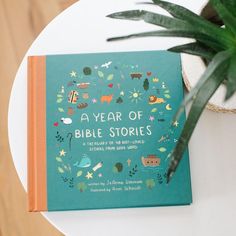 a green book sitting on top of a white table next to a potted plant