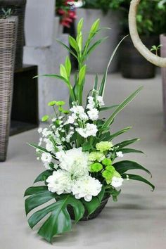 an arrangement of white flowers and greenery in a pot