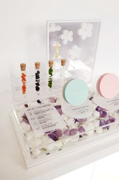 an assortment of beauty products displayed in a clear case on a white surface with flowers