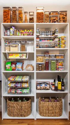 an organized pantry with white shelving and wicker baskets on the bottom shelf filled with food