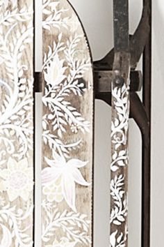 an iron gate with white flowers and leaves painted on it