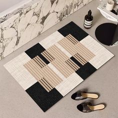 a pair of black shoes sitting on top of a bathroom floor next to a rug