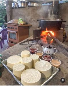 several different types of cheese on a tray in front of an open fire place with pots and pans