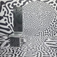 a bathroom with black and white designs on the walls, toilet paper rolls in front of it