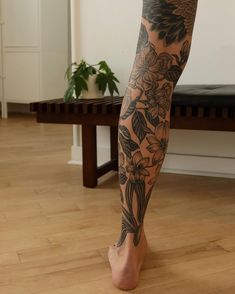 a woman's legs with tattoos on them and flowers in the bottom right leg