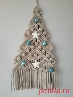 a crocheted christmas tree hanging on a wall with beads and starfishs