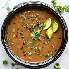 a pot filled with black beans and limes on top of a marble countertop