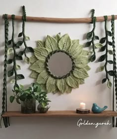 a shelf with some plants on it and a mirror in the middle that has leaves hanging from it