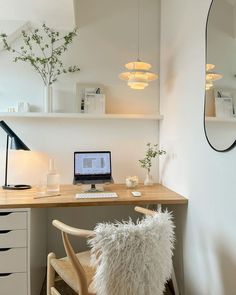 a laptop computer sitting on top of a wooden desk next to a lamp and mirror