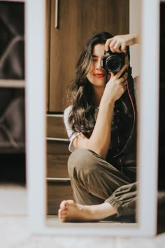 a woman sitting on the floor with a camera