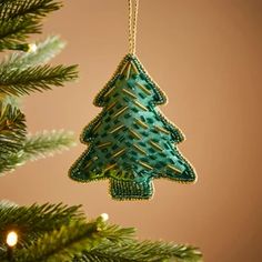 a green christmas tree ornament hanging from a pine tree